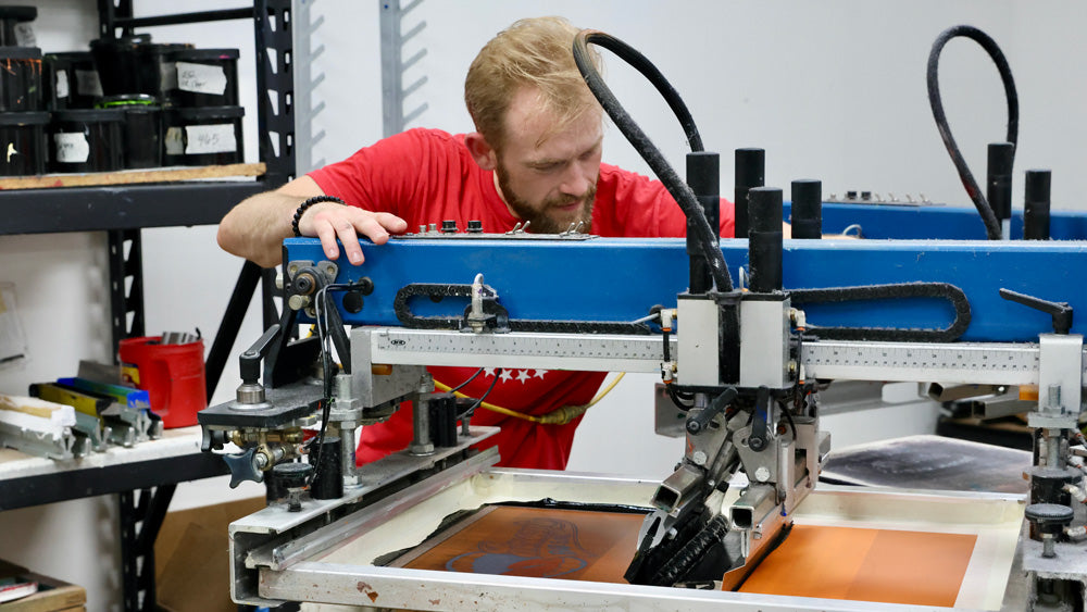 Advanced Sportswear employee screen printing a customer's order